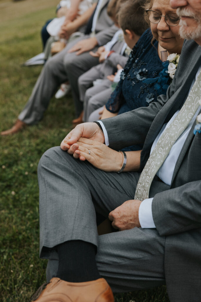 Groom's parents holding hands during ceremony