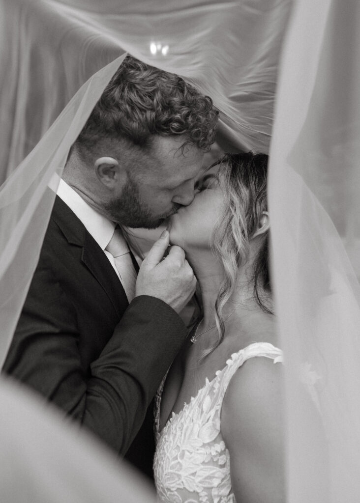 Bride and Groom kissing under veil 