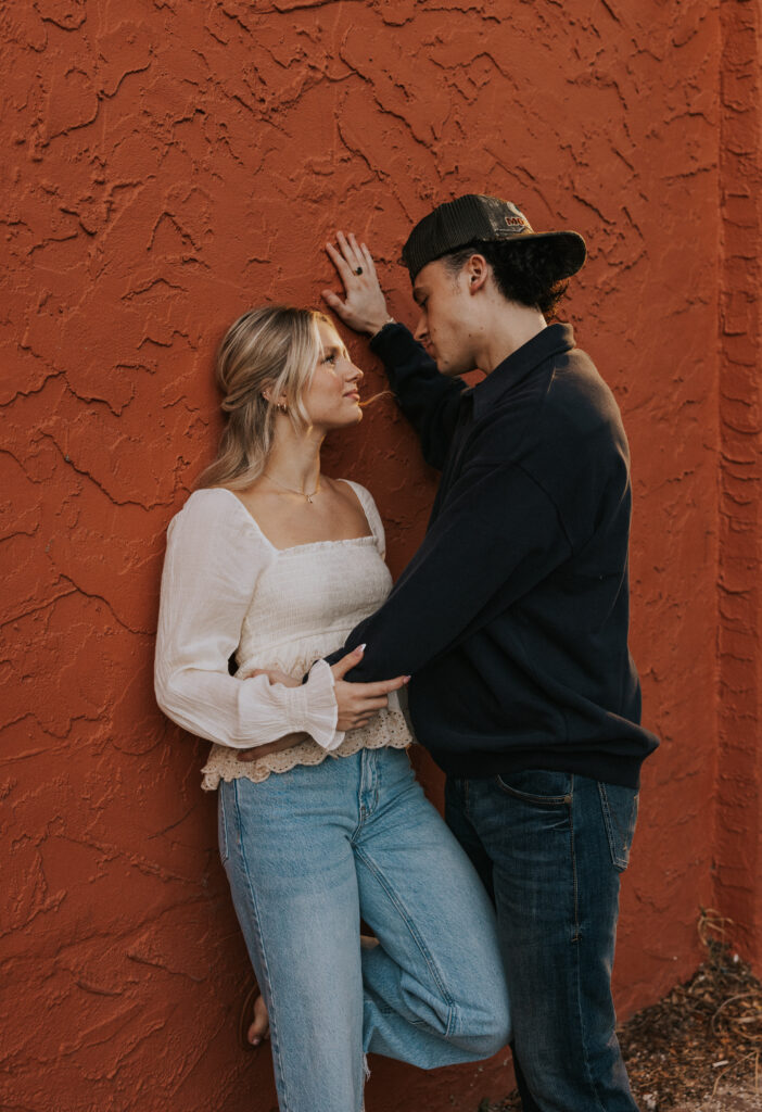 Couple posing on bold color wall for engagement session