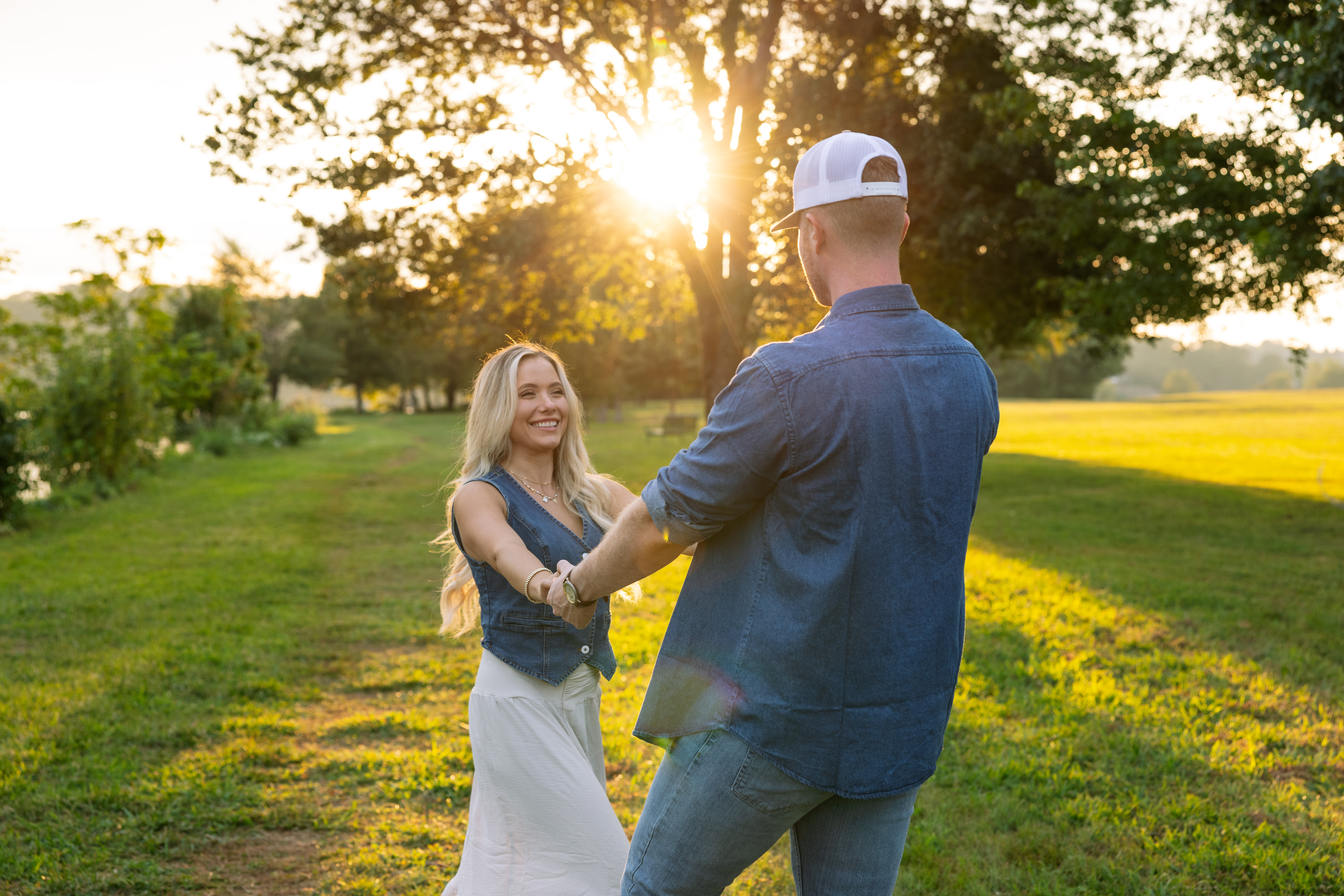 Close-up of an engaged couple embracing at golden hour in a scenic field, modern Western engagement photography in Knoxville with bright sunflare