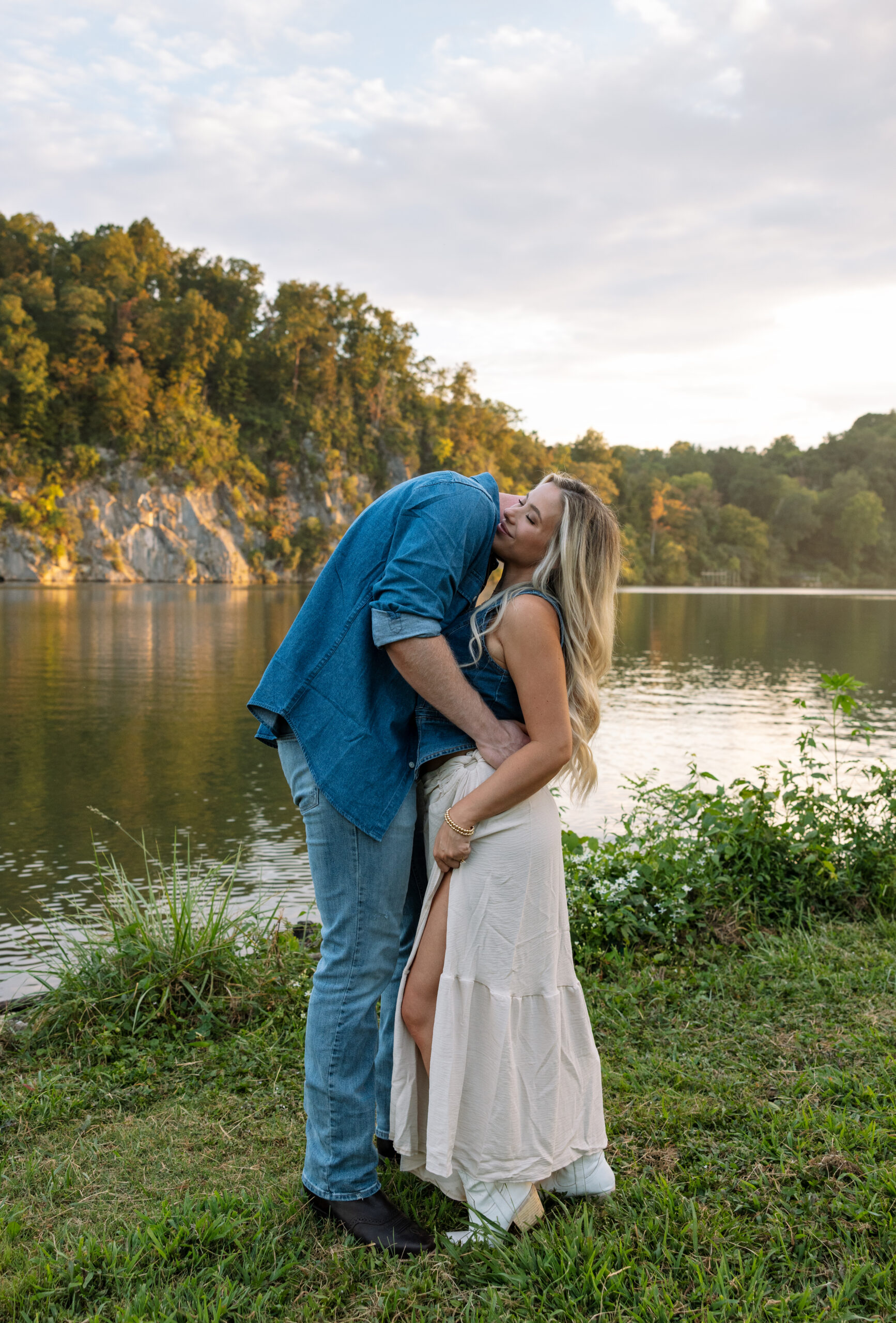 Close-up of an engaged couple embracing at golden hour in a scenic field, modern Western engagement photography in Knoxville with soft, glowing light.