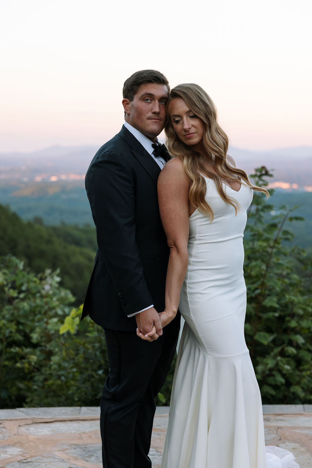 Bride and groom holding hands at golden hour with the Smoky Mountains behind them, captured by a Knoxville wedding photographer at The Trillium Venue