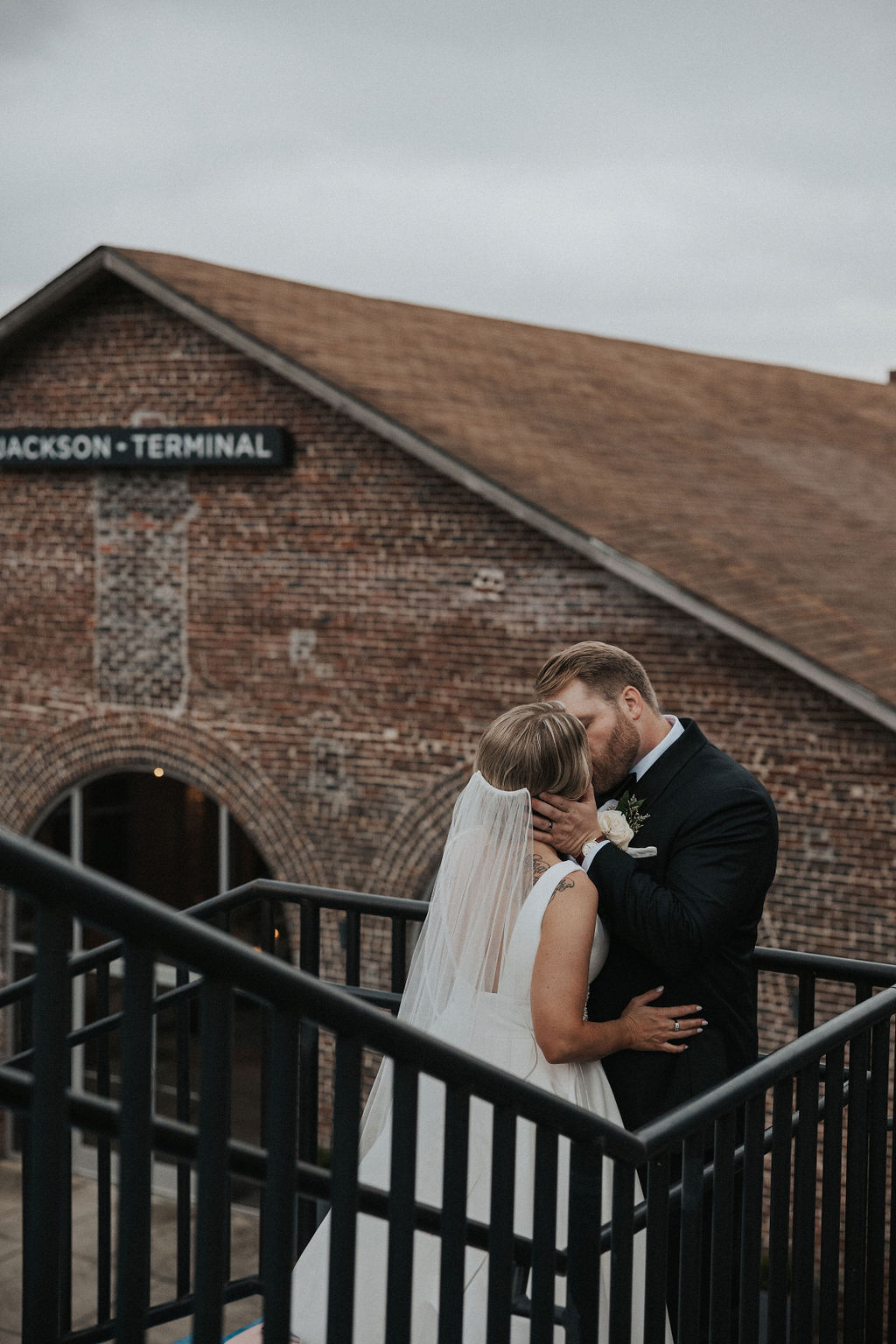 Framed by the rustic charm of Jackson Terminal, this romantic kiss captures the spirit of a Knoxville courthouse wedding. The bride and groom share an intimate moment on the staircase, their embrace full of warmth and connection. It's a beautifully authentic image captured by a Knoxville wedding photographer.