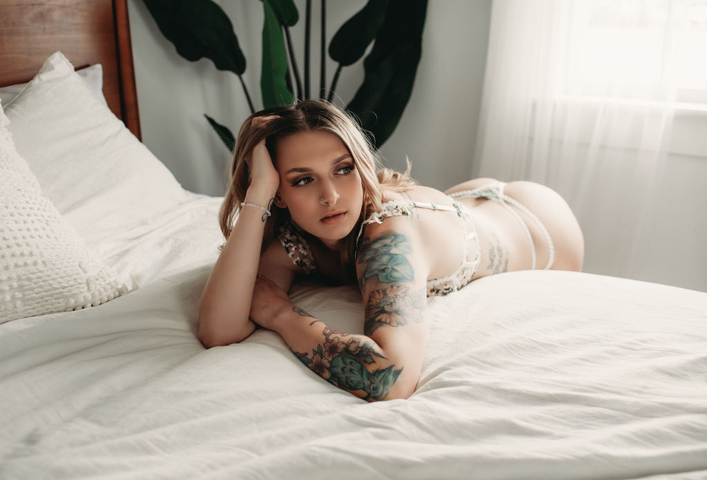 Woman wearing cream set while leaning over bed during boudoir photography shoot. 