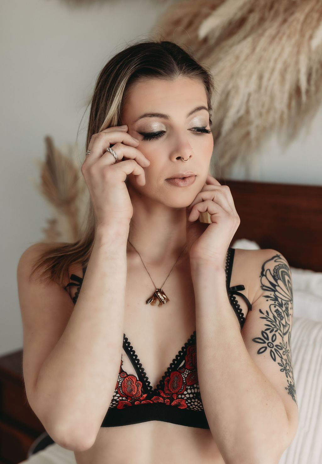 Boudoir photographer close-up portrait of a woman adjusting her hair on a bed, soft neutral tones and gentle window light.