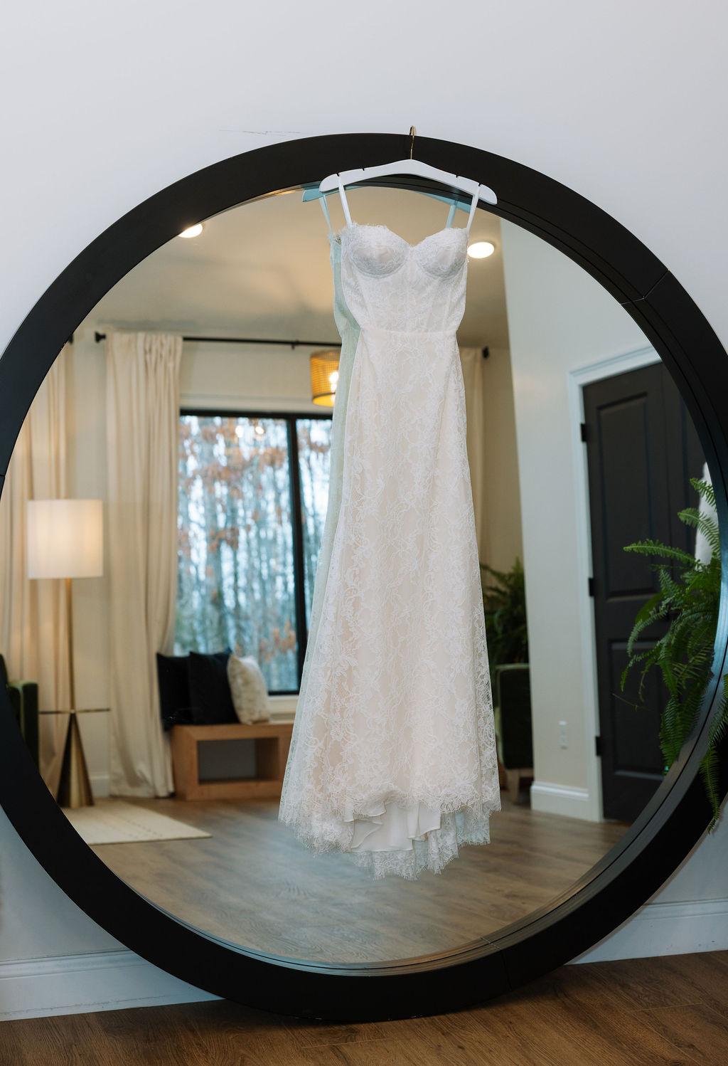 Lace wedding dress hanging in a round mirror inside the getting-ready suite at Nichols Heir, capturing the quiet beginning of a Tennessee wedding morning.