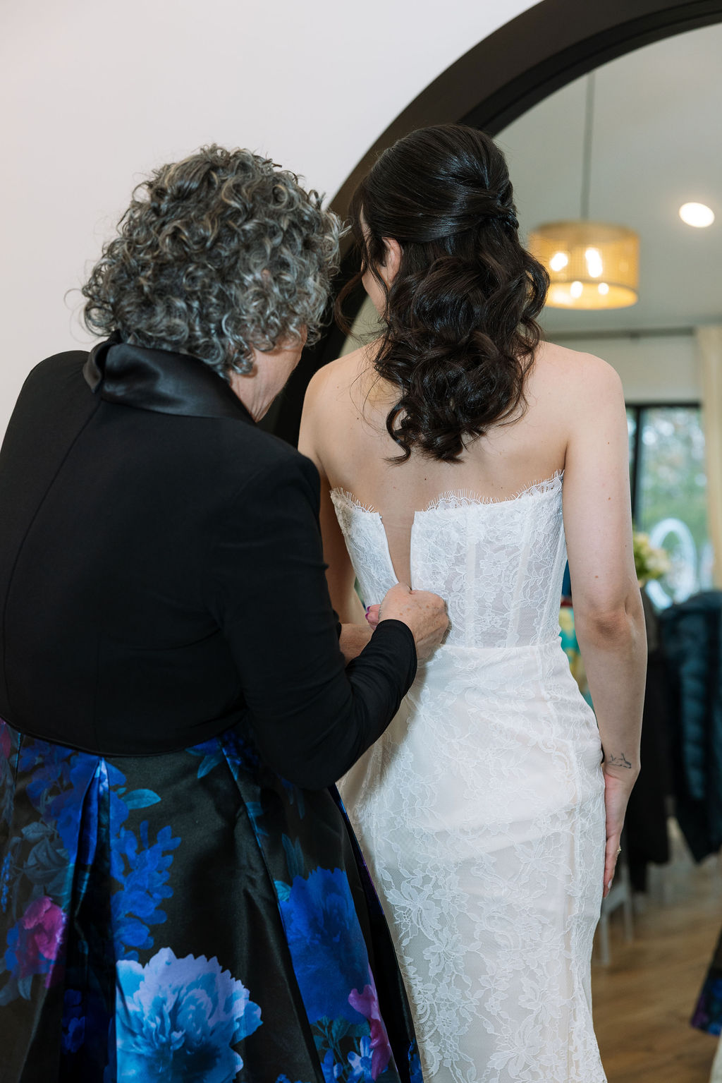 Bride getting ready at Nichols Heir in Tennessee as her mother buttons her lace gown before the ceremony, a quiet moment that reflects what do wedding planners do behind the scenes to protect the morning’s calm.