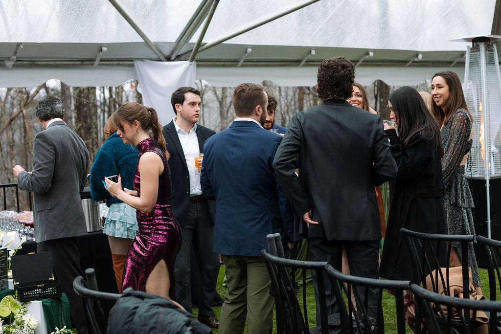 Guests mingling during cocktail hour under a tent at a rainy Tennessee wedding, a smooth transition that reflects what do wedding planners do to guide flow between ceremony and reception.