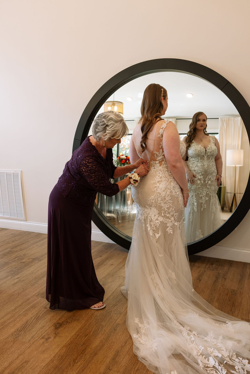 Bride's mother buttons up her wedding dress before wedding ceremony at Smoky Mountain wedding venue. 
