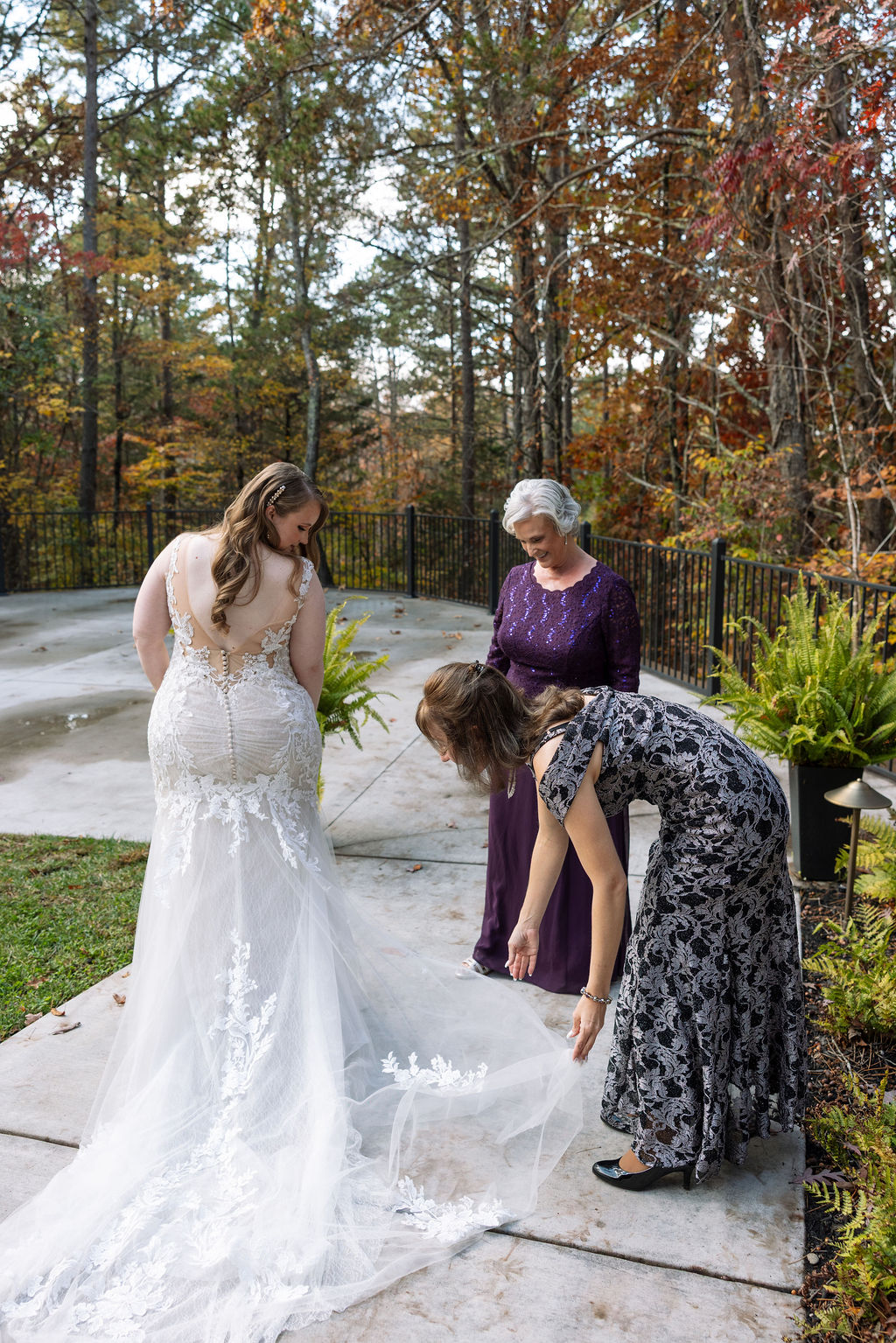 Family fanning out bride's wedding dress and train outside.