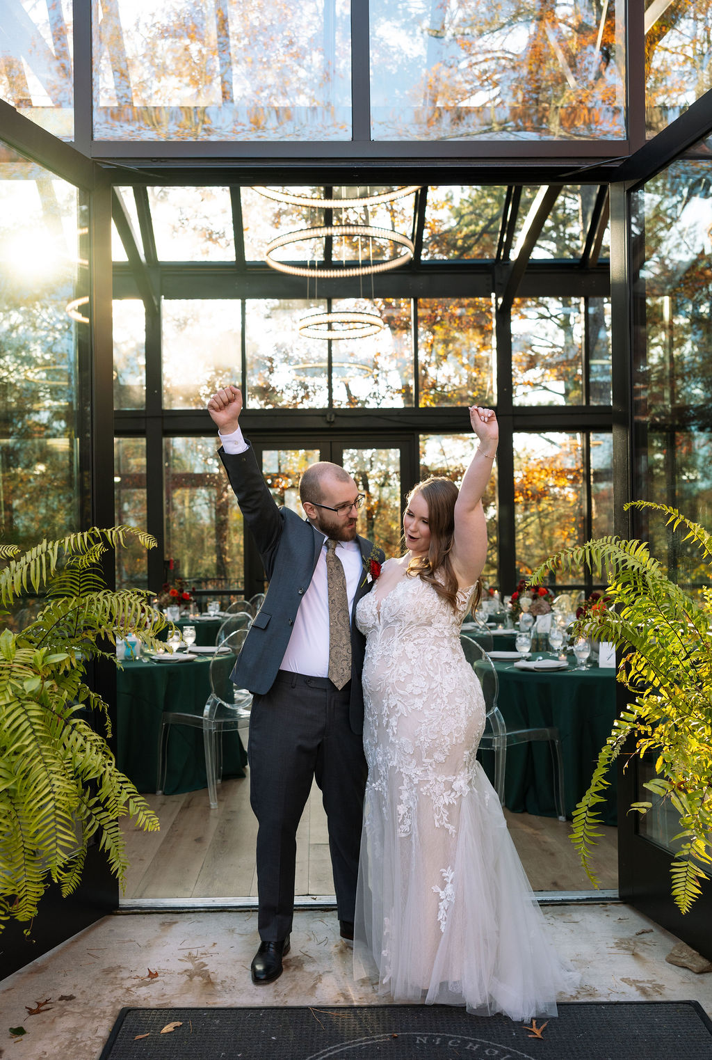 Bride and groom celebrating their reception entrance at a Smoky Mountain wedding venue, framed by greenery and warm interior light.