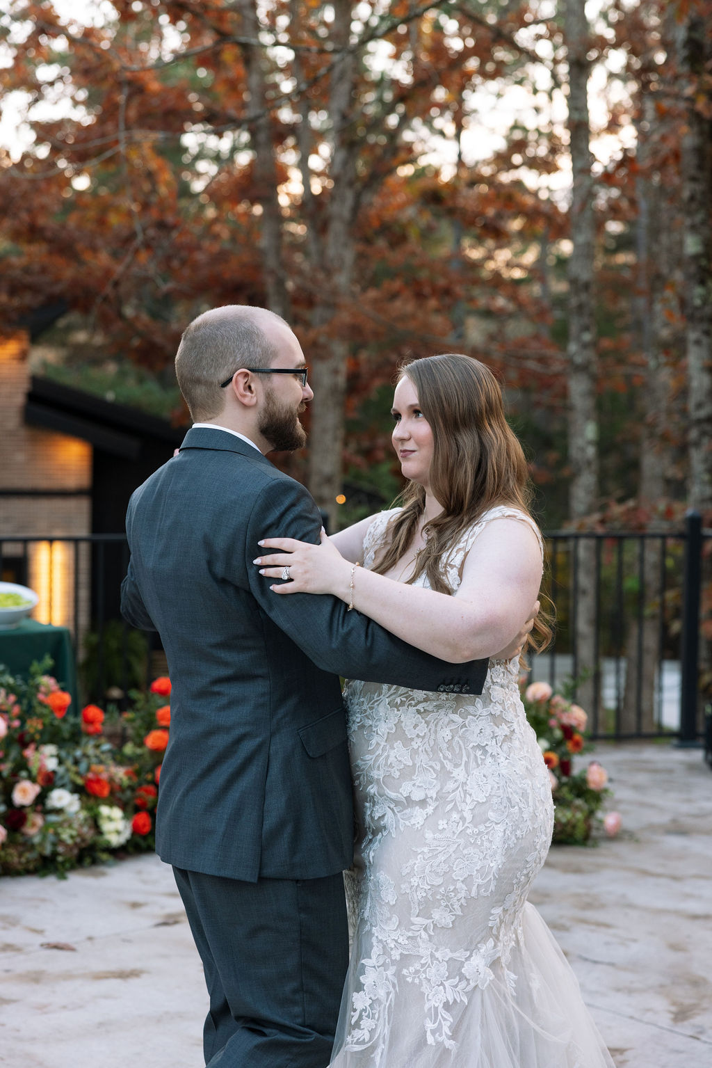 Bride and groom sharing a quiet dance outdoors at a Smoky Mountain wedding venue, surrounded by fall trees and soft evening light.