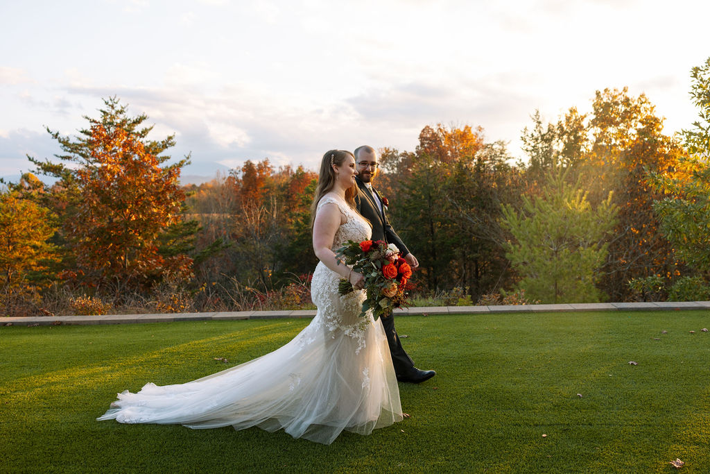 Newly married couple walking together at a Smoky Mountain wedding venue, framed by fall foliage and mountain views.