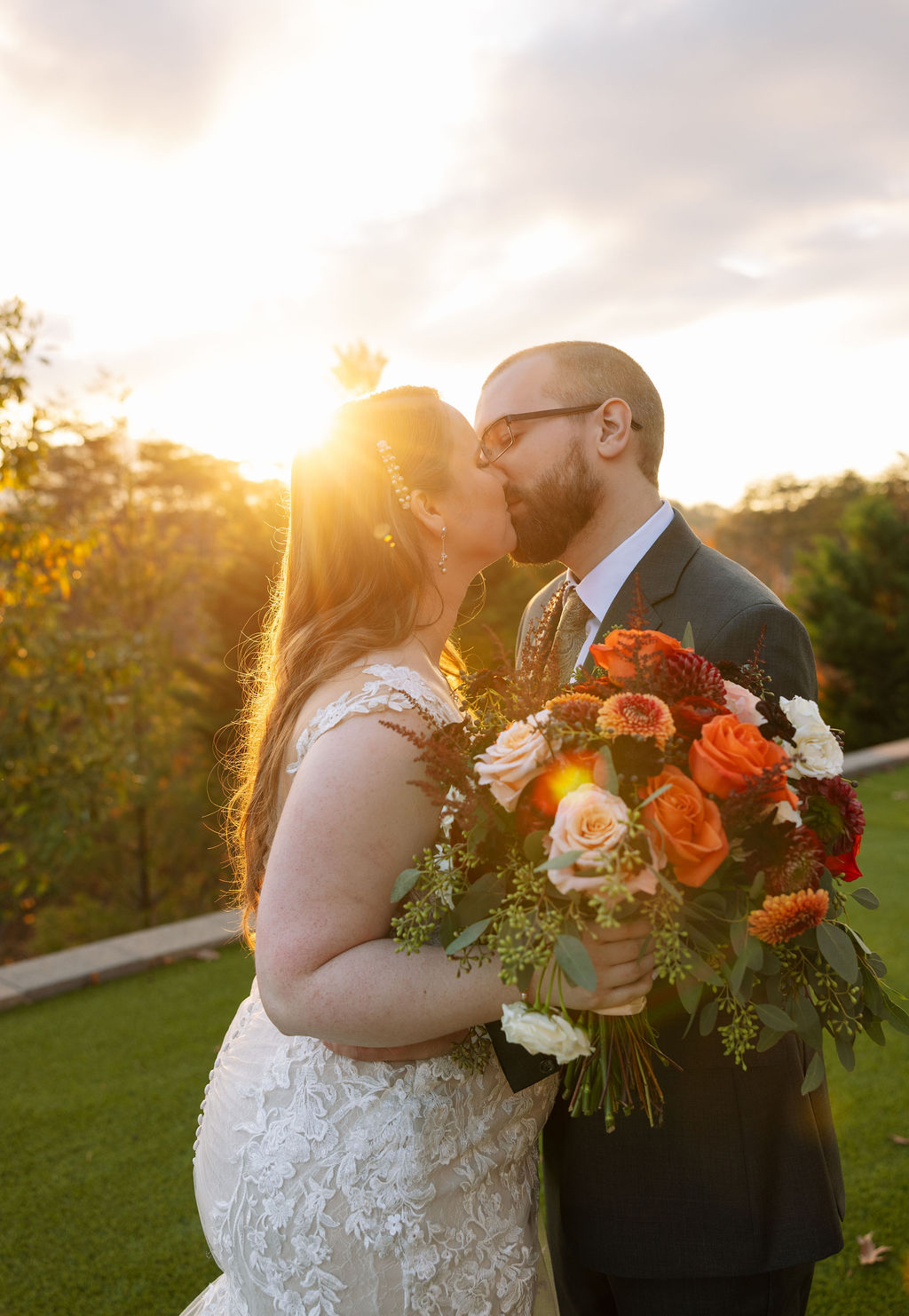 Bride and groom kiss at golden hour while embracing after intimate outdoor wedding ceremony in the Smoky Mountains. 