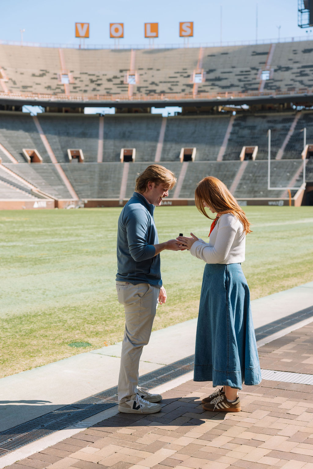 Man placing engagement ring on partner during surprise proposal at Neyland Stadium