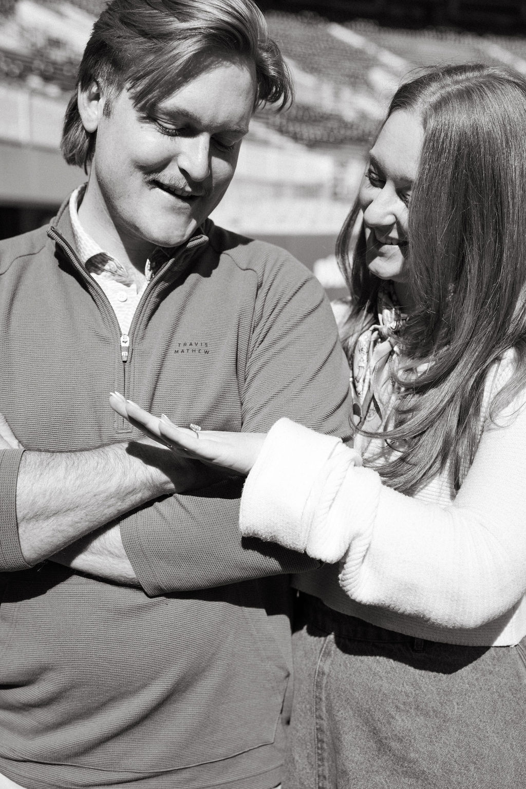 Black and white portrait of couple admiring engagement ring after Neyland Stadium proposal
