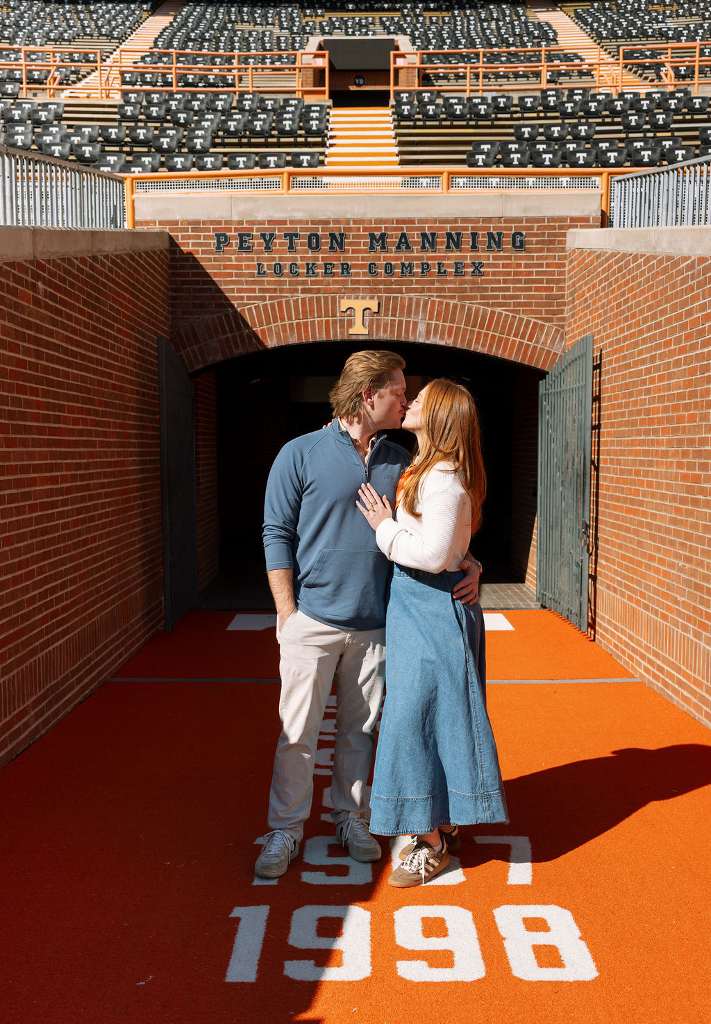 Engaged couple kissing at Peyton Manning Locker Complex entrance at Neyland Stadium