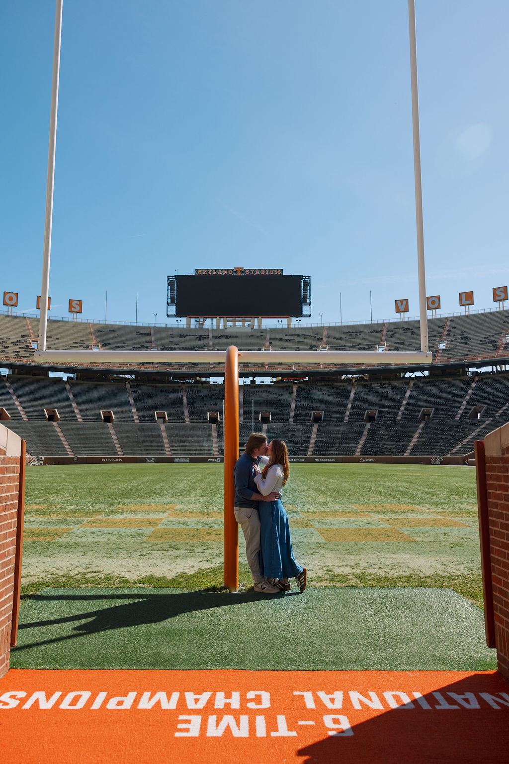 Newly engaged couple kissing under goalpost during engagement photos at Neyland Stadium