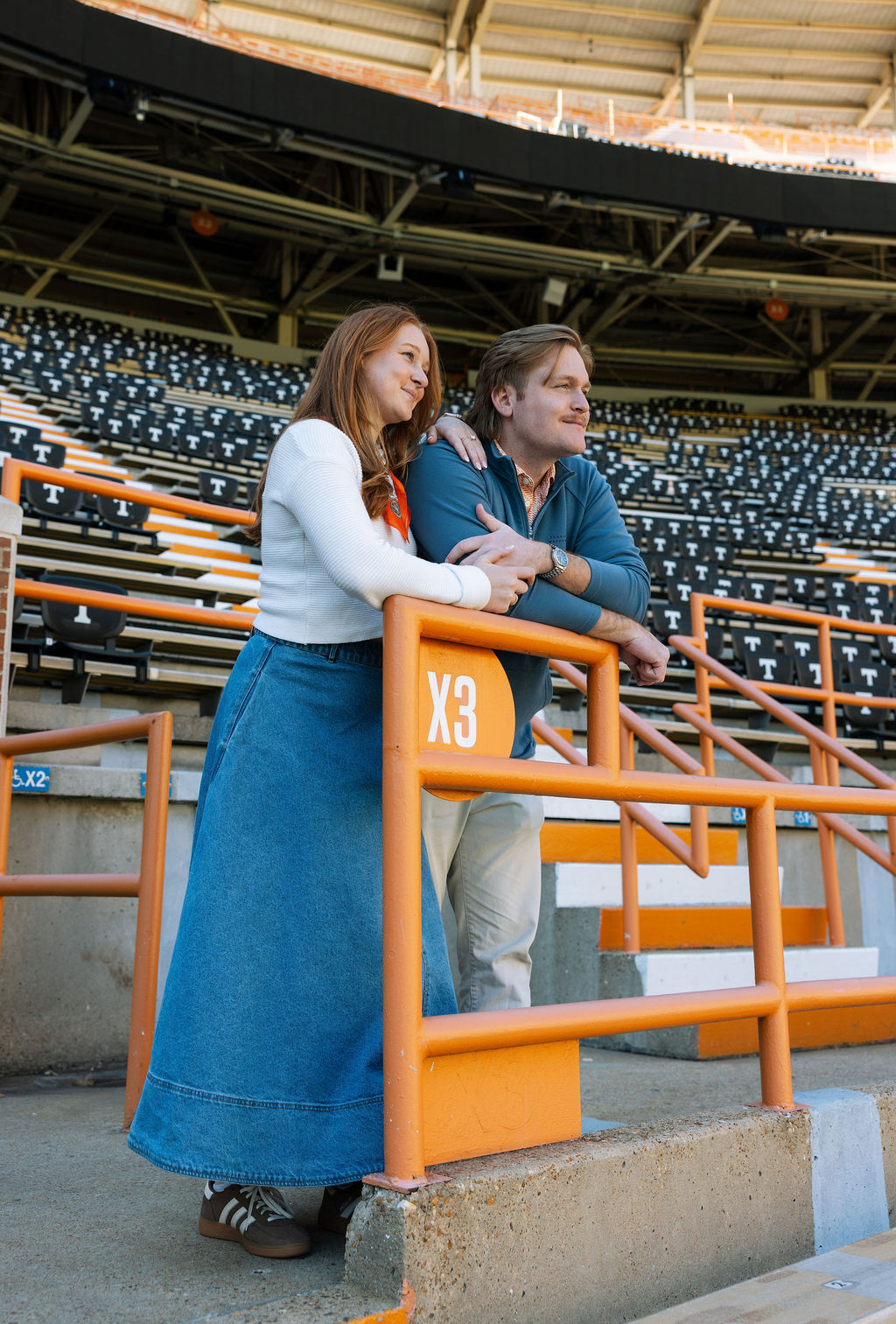 Couple leaning on Neyland Stadium railing during Knoxville engagement photos