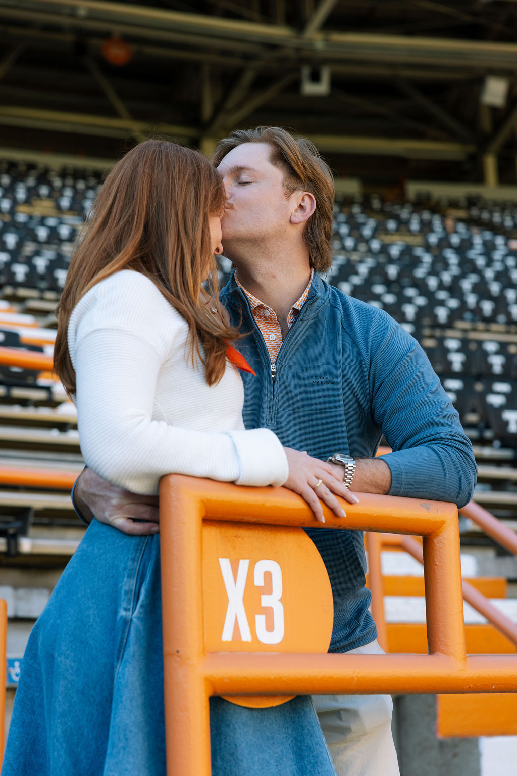 Romantic engagement photo of couple kissing in Neyland Stadium seating section