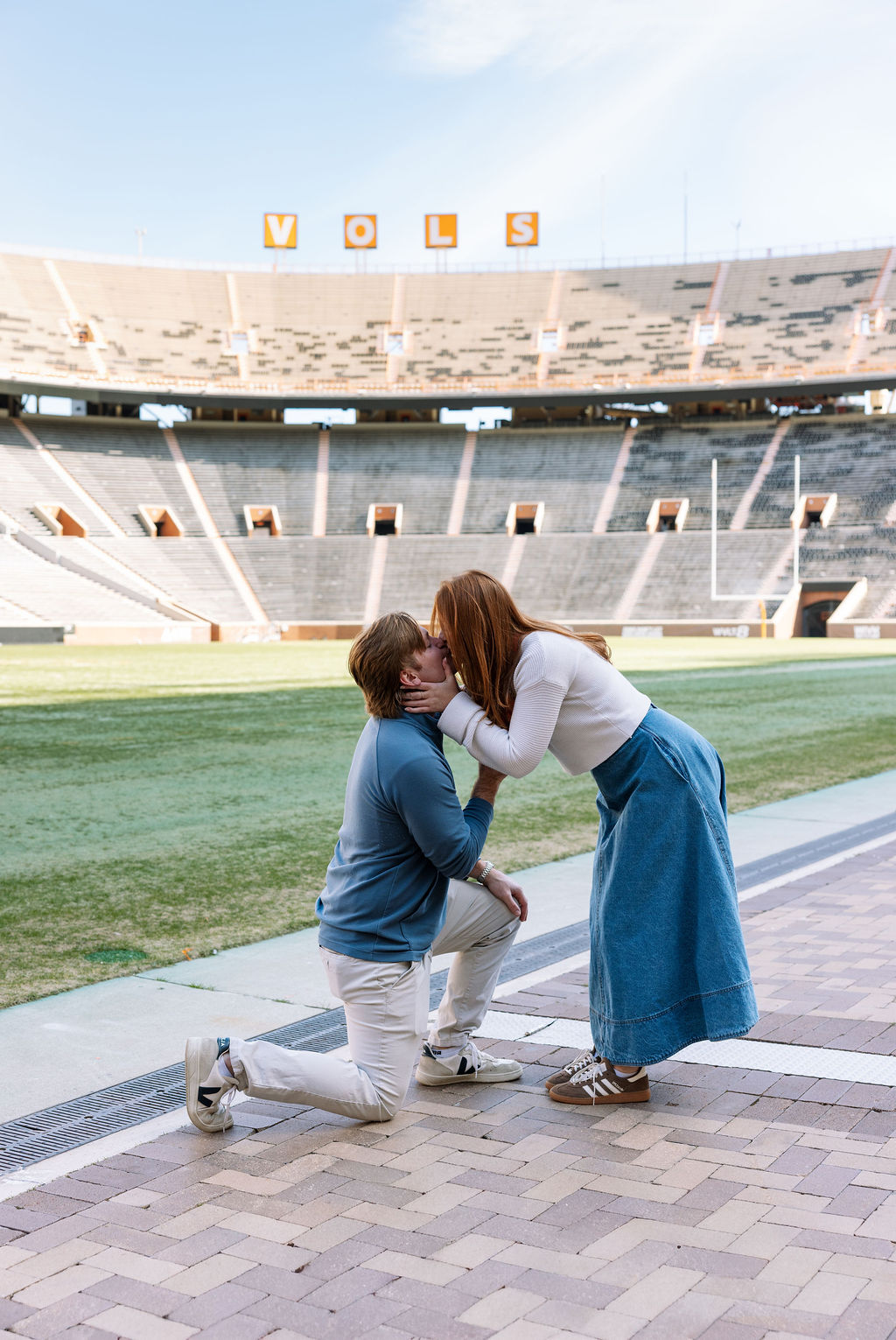 Couple kissing during surprise proposal moment on Neyland Stadium field in Knoxville