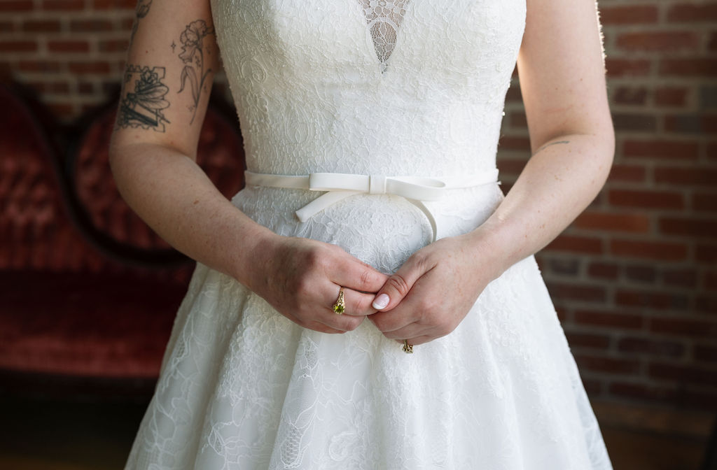 Close-up of bride’s hands resting on a lace wedding dress with soft natural light