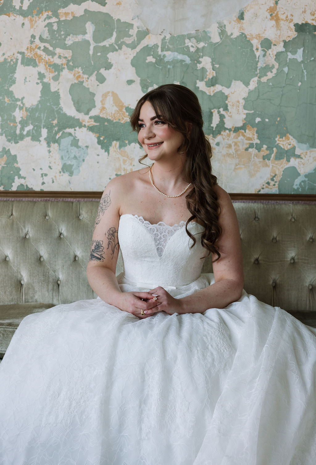Bride sitting on a velvet couch in a lace wedding gown with soft natural light, photographed by a wedding photographer in Knoxville