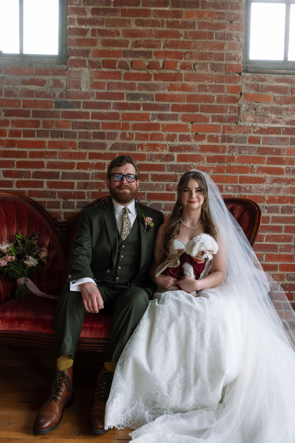 Bride and groom sitting together with their dog on a vintage couch, photographed by a wedding photographer in Knoxville