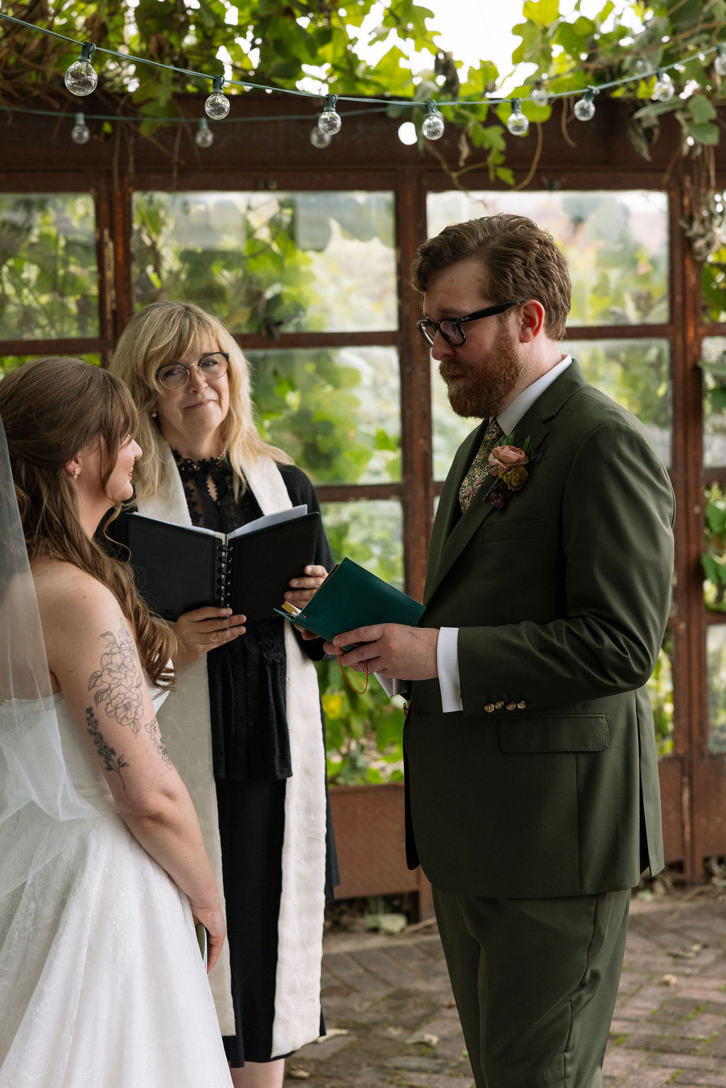 Bride and groom exchanging vows during an intimate ceremony under greenery, photographed by a wedding photographer in Knoxville