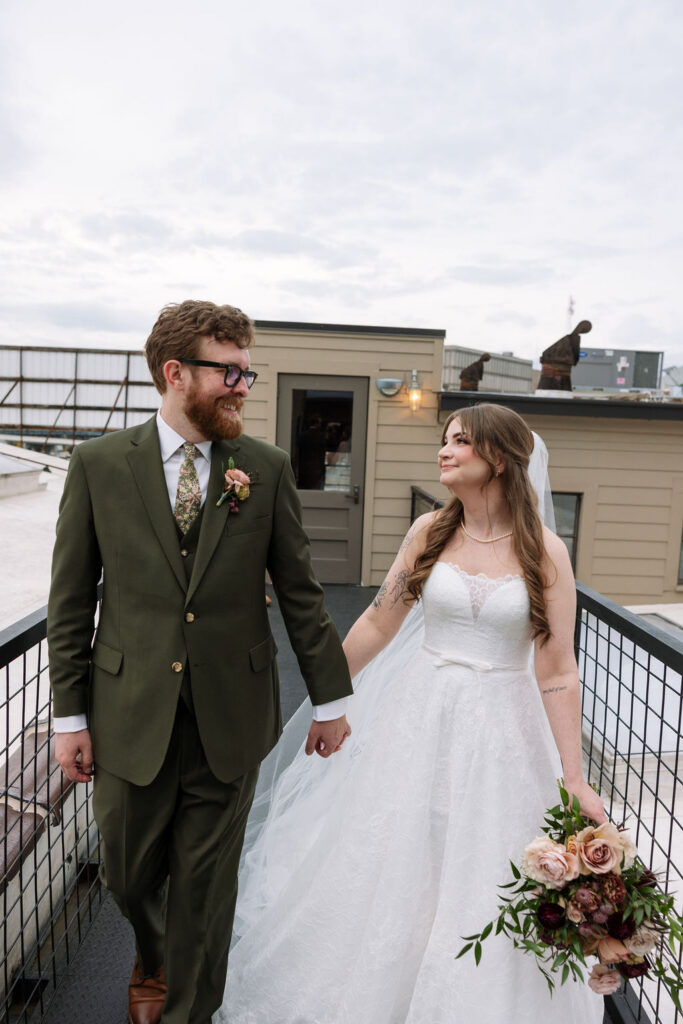 Bride and groom walking hand in hand on a rooftop space, photographed by a wedding photographer in Knoxville