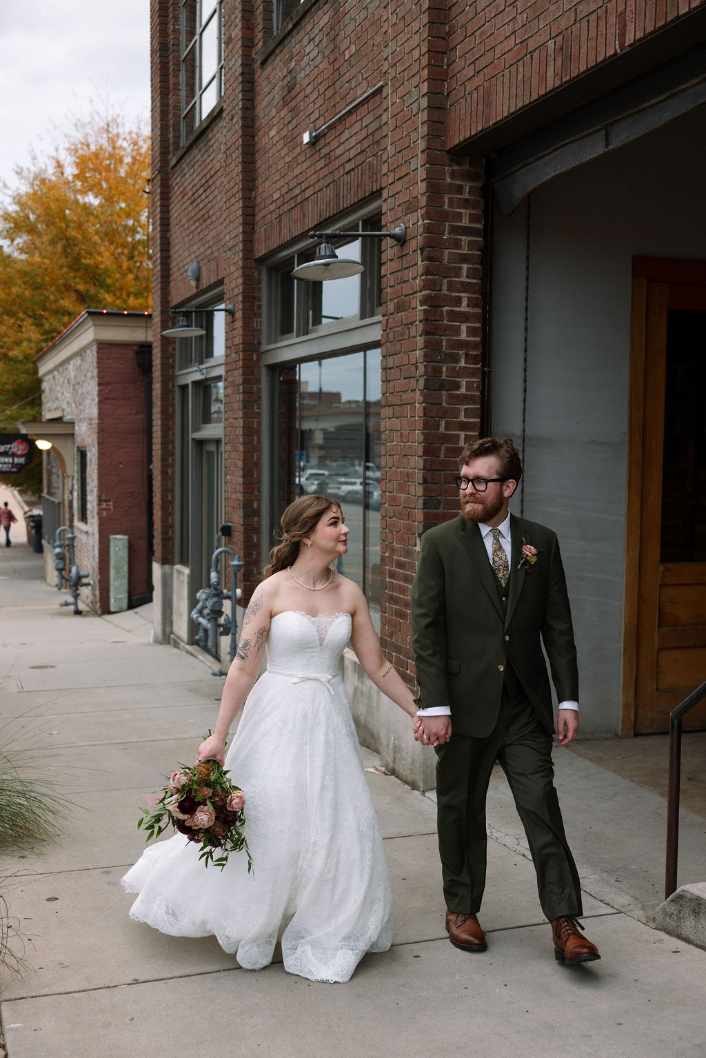 Bride and groom walking together along a downtown sidewalk outside an industrial wedding venue