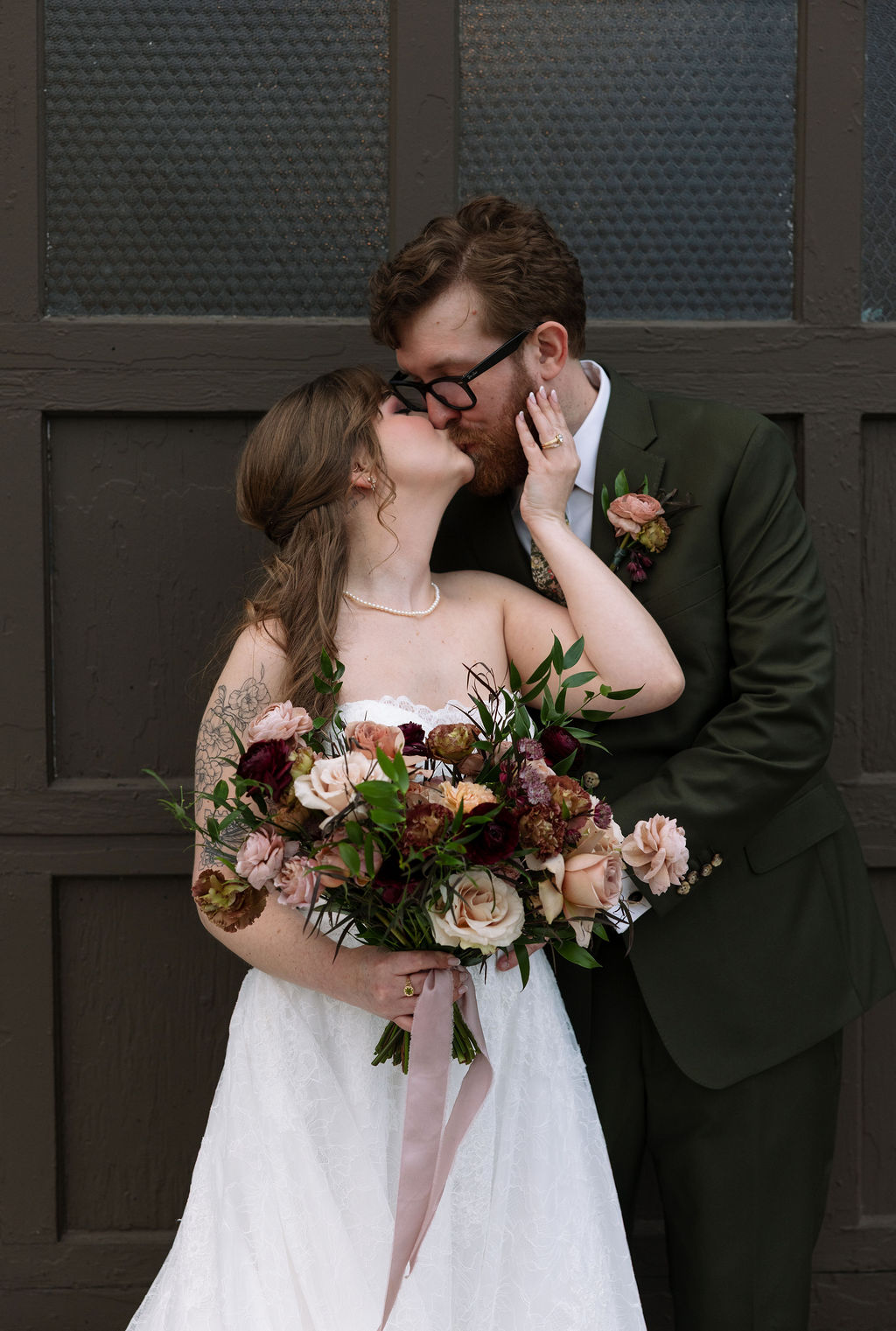 Bride and groom kissing while holding a textured floral bouquet, photographed by a wedding photographer in Knoxville