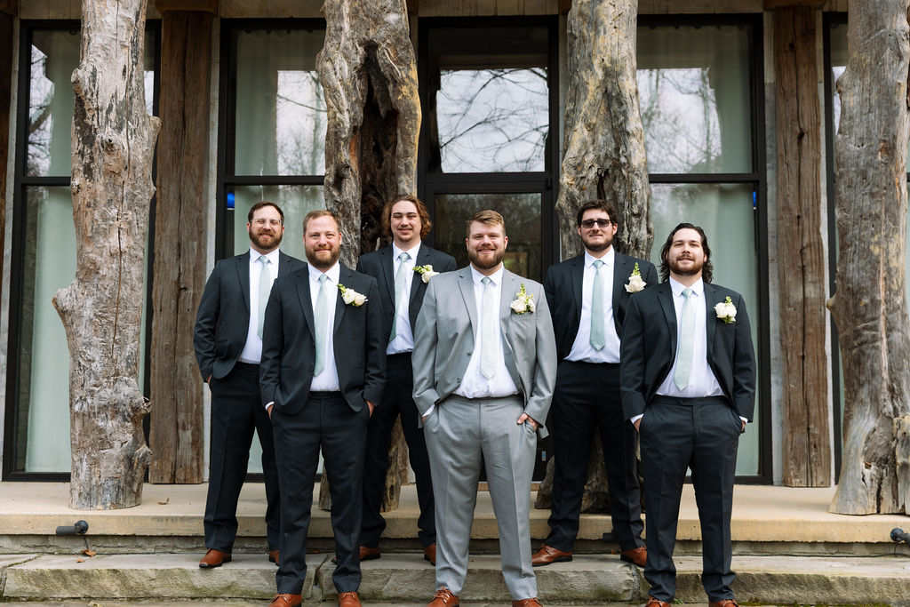 Groom and groomsmen portrait outside rustic Tennessee wedding venue before ceremony
