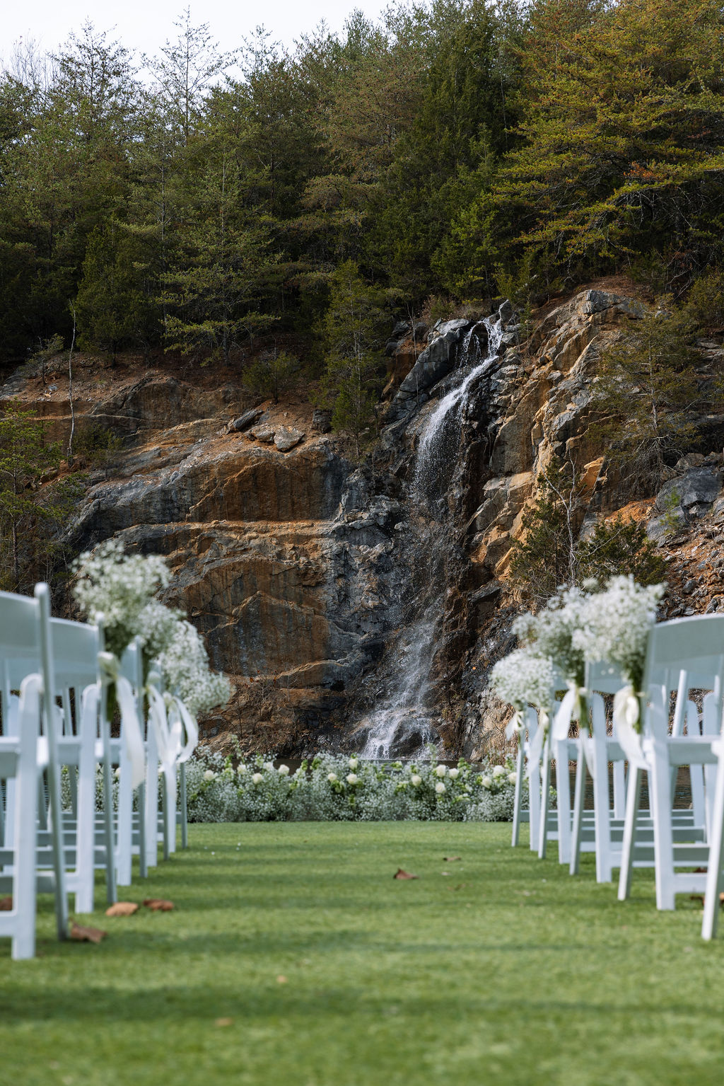 Ceremony aisle view toward waterfall during candid wedding photography at Tennessee outdoor venue