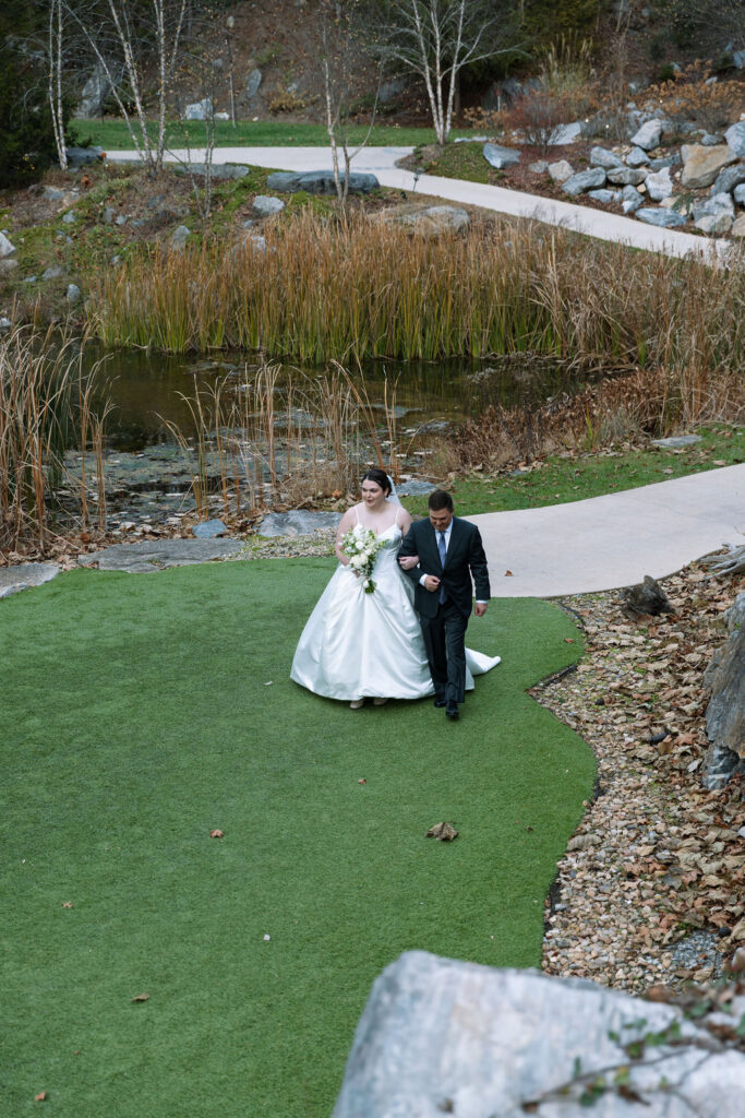 Bride walking with father toward outdoor ceremony aisle during candid wedding photography moment