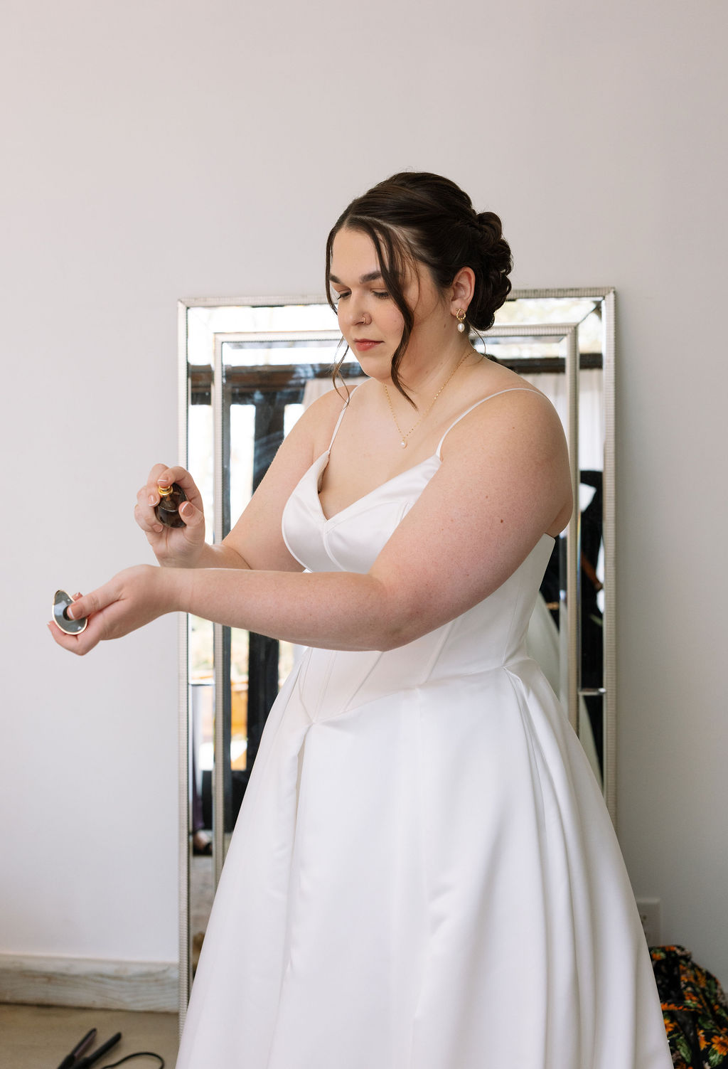 Bride applying perfume while getting ready during calm candid wedding photography preparation moment