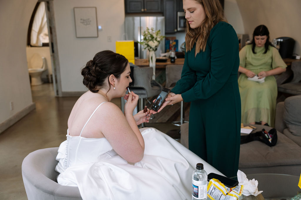 Bride having makeup touched up while getting ready during calm candid wedding photography moment