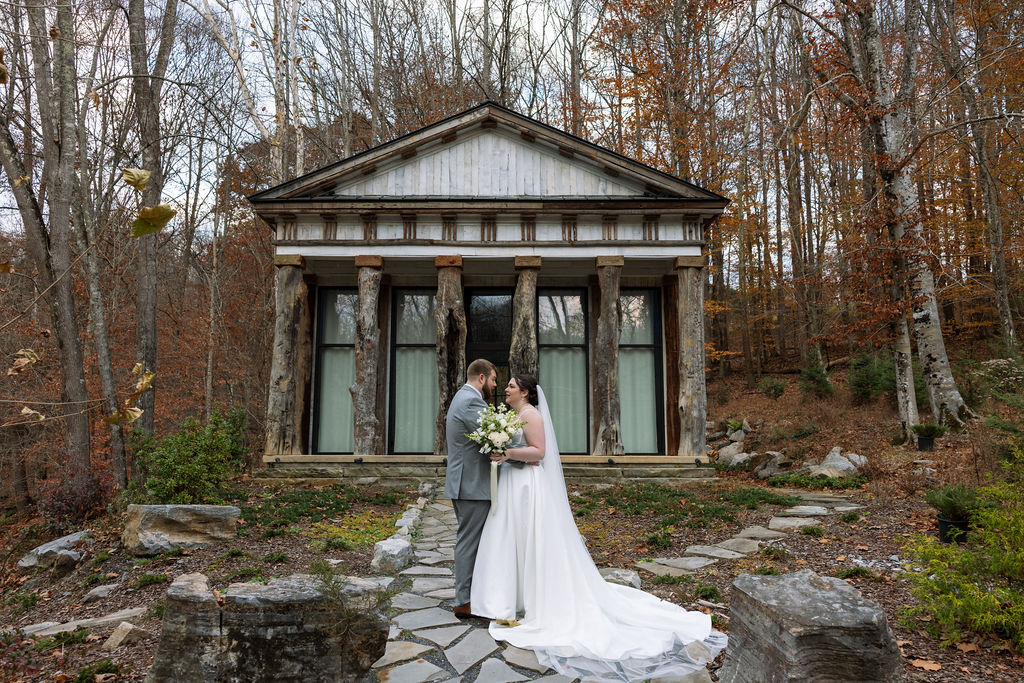 Bride and groom standing together outside rustic stone column venue during Knoxville wedding portraits