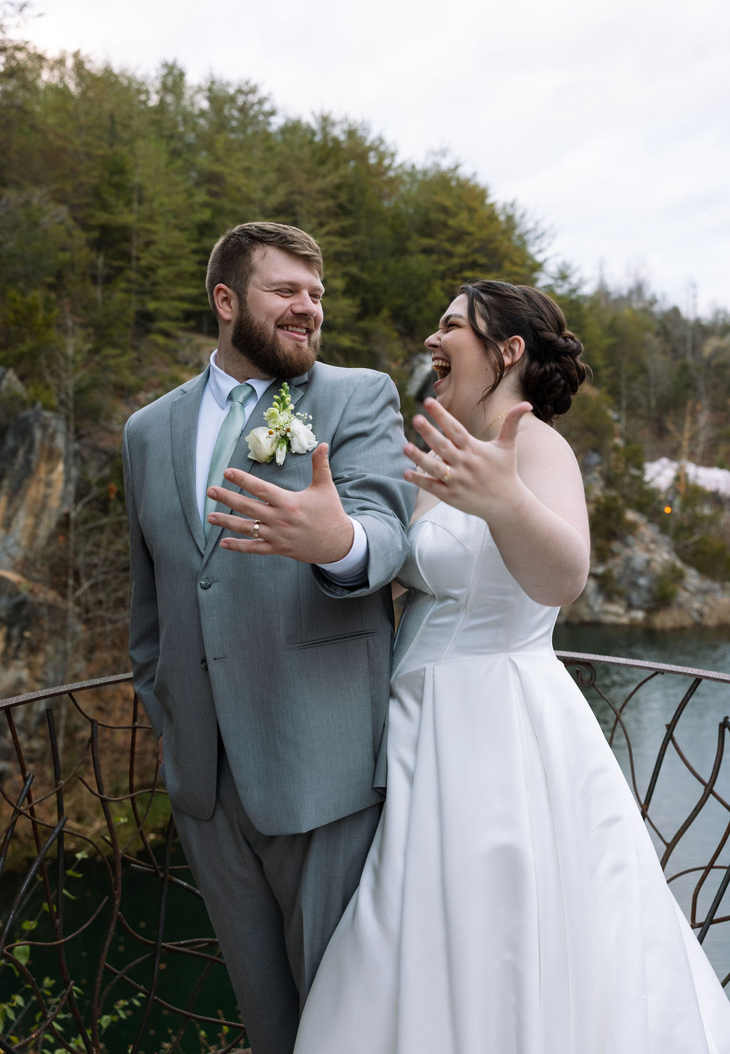 Bride and groom laughing together on waterfall overlook during candid wedding photography portraits