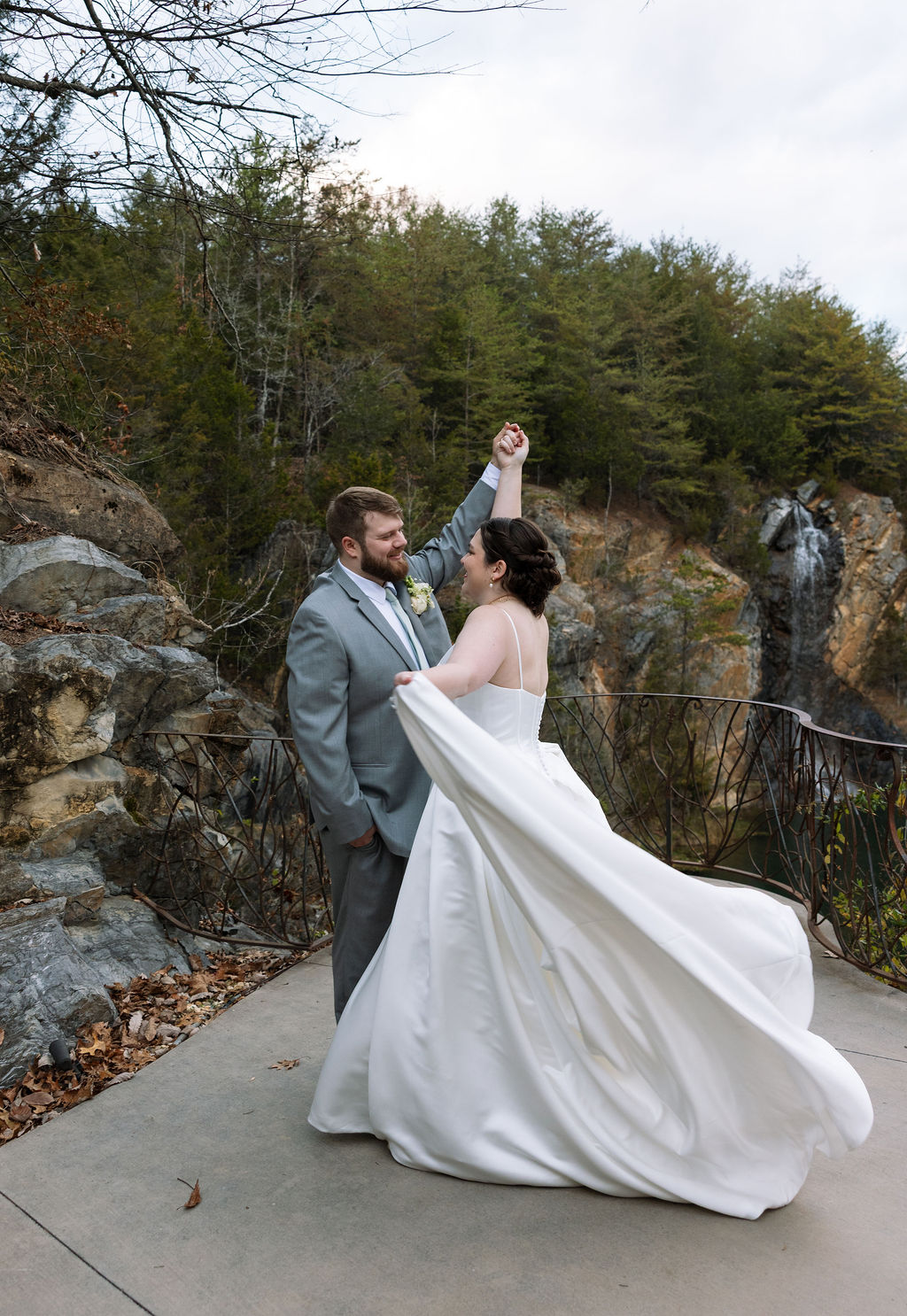 Bride twirling with groom on overlook captured during candid wedding photography portraits