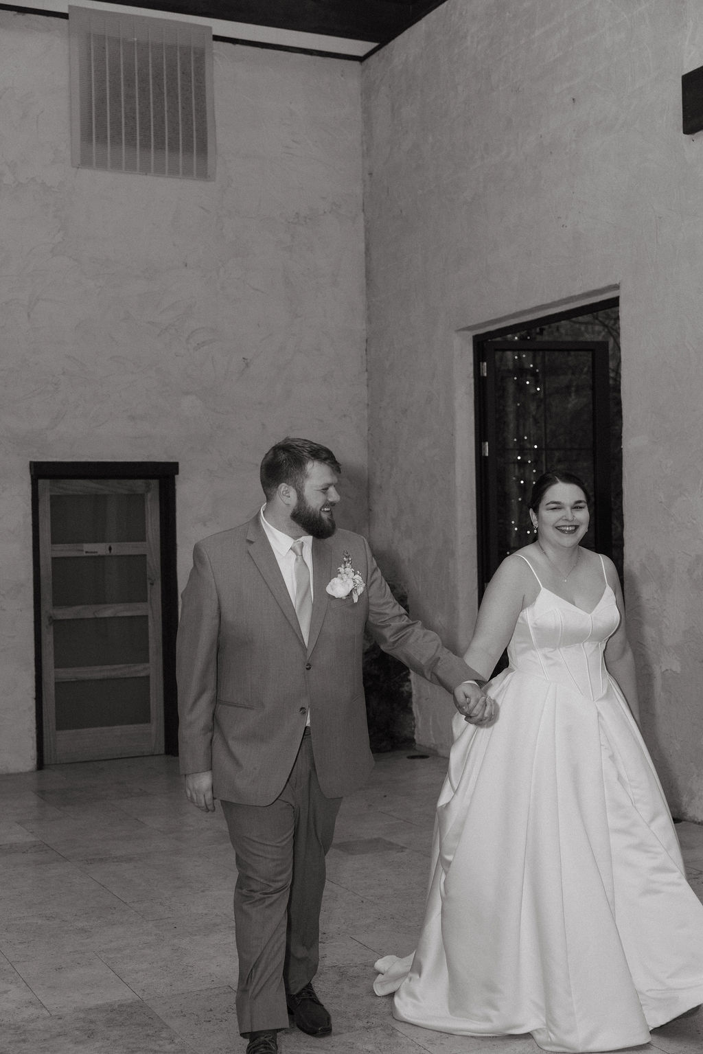 Newly married couple walking into reception space holding hands during candid wedding photography