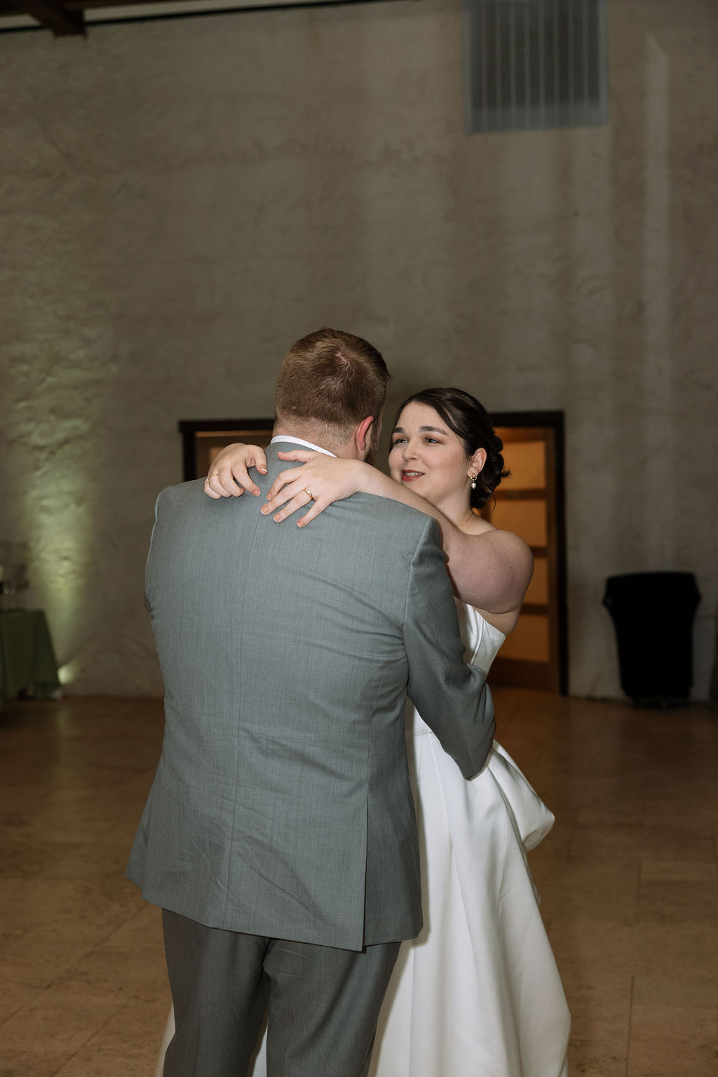 Bride and groom sharing first dance during indoor reception captured with candid wedding photography