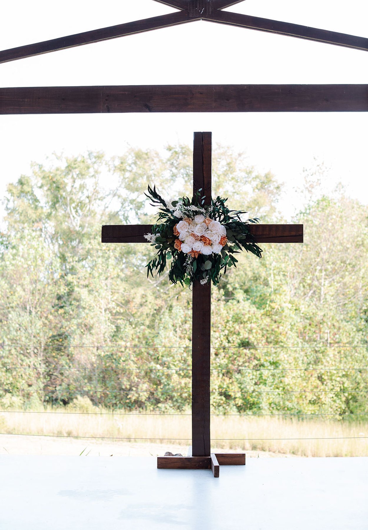 Tennessee wedding ceremony cross with floral arrangement and natural backdrop