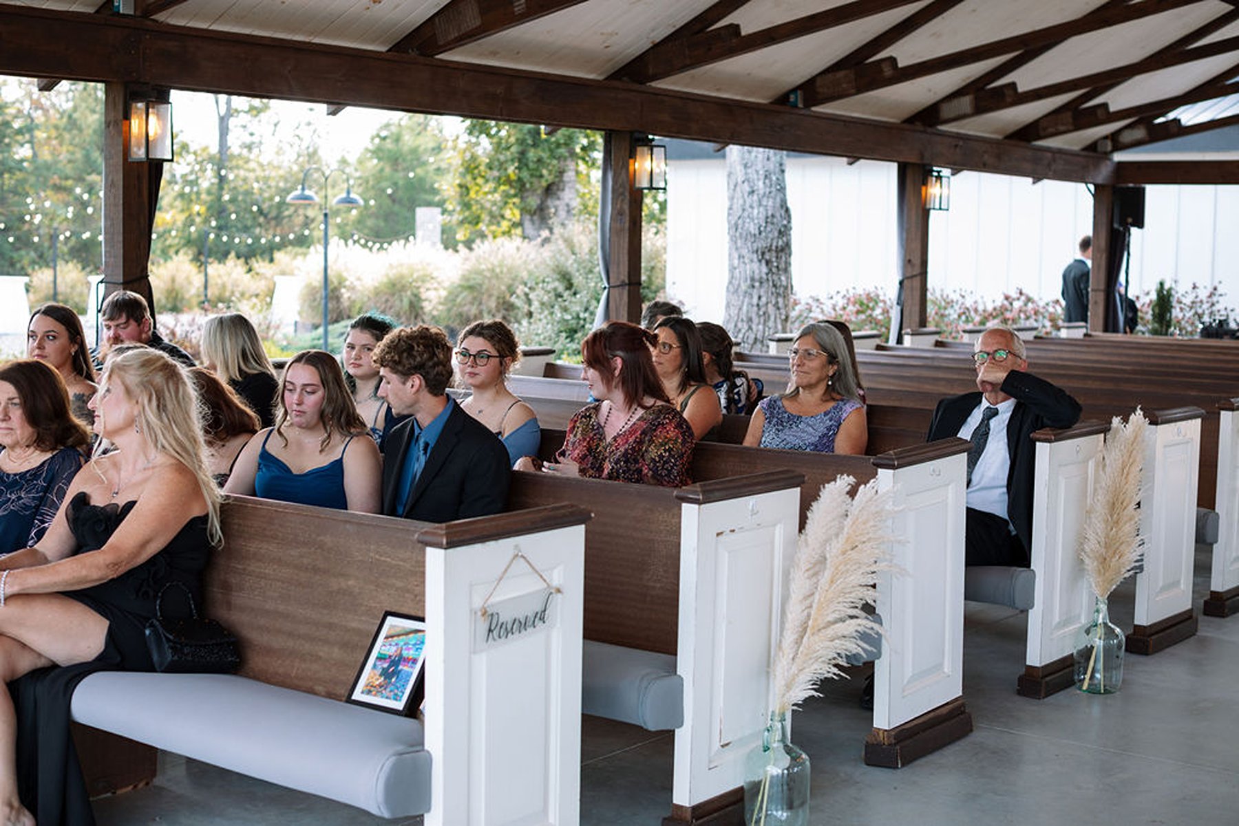 Guests seated in wooden pews during ceremony in open-air chapel