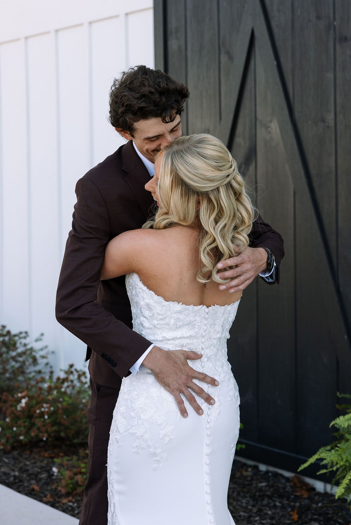 Tennessee wedding couple embracing beside black barn doors in soft daylight