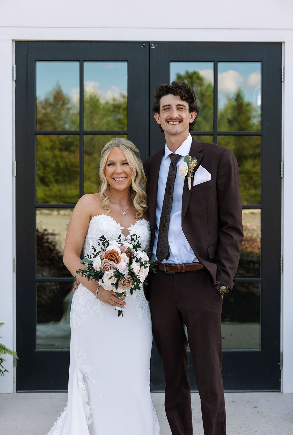 Bride and groom portrait in front of black barn doors with bouquet