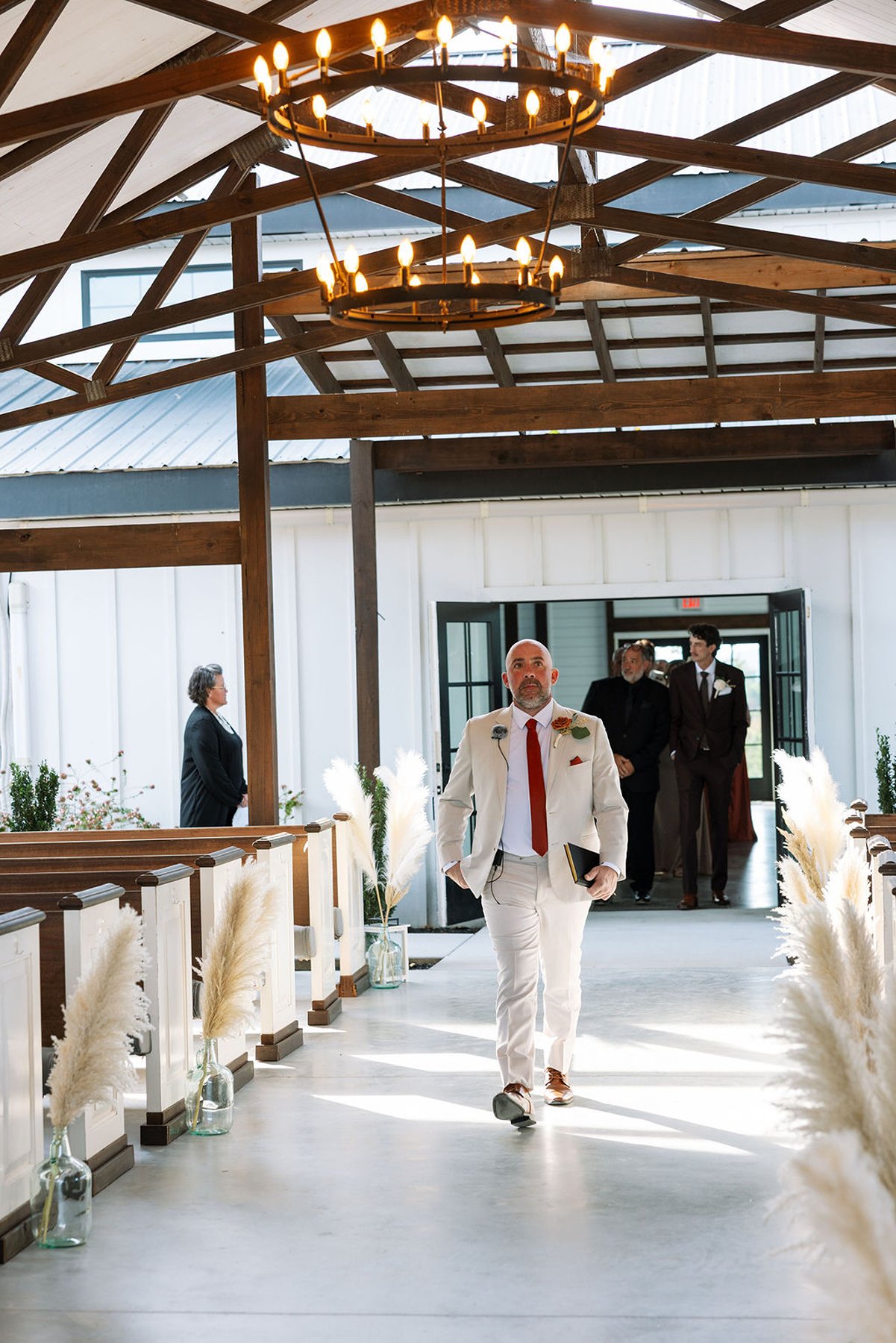 Groomsman walking down aisle holding book during ceremony processional