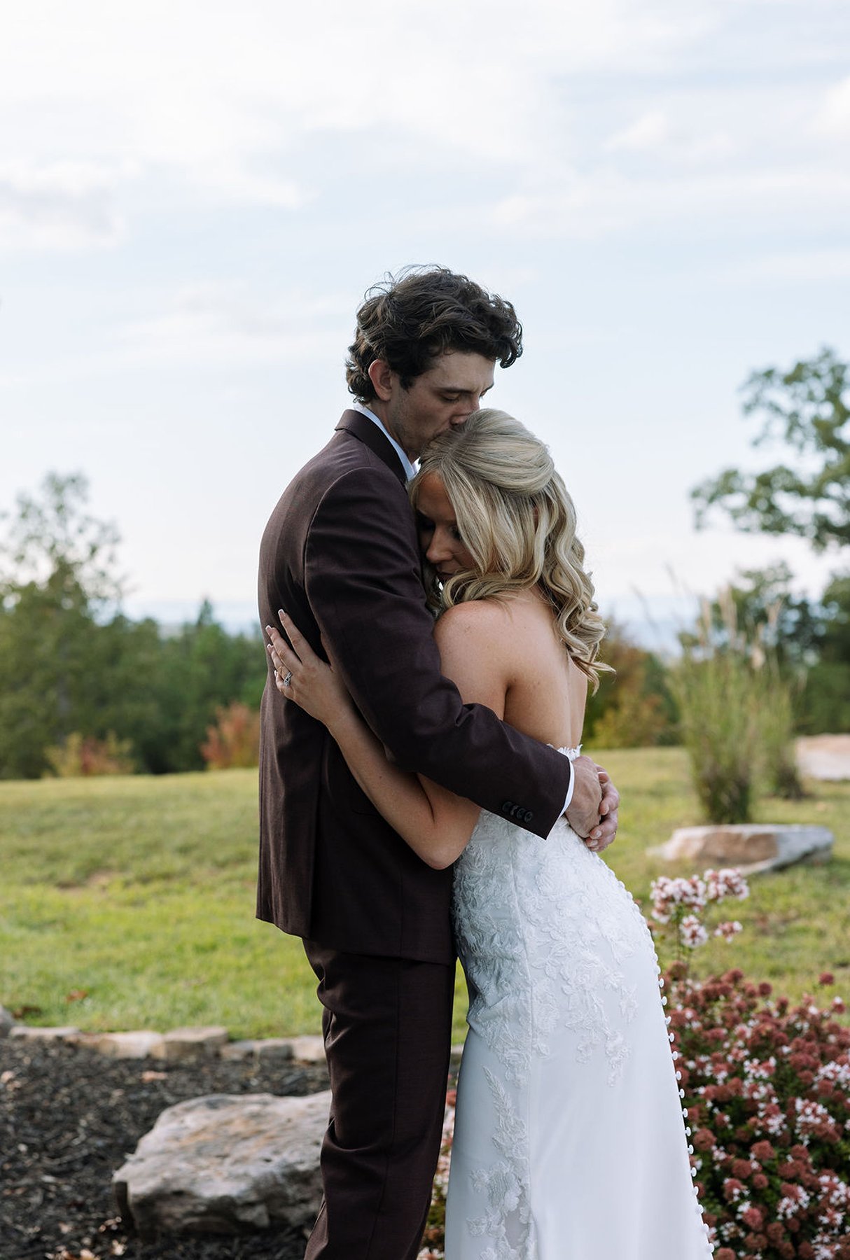 Bridesmaids helping bride with dress and laughing outside modern venue