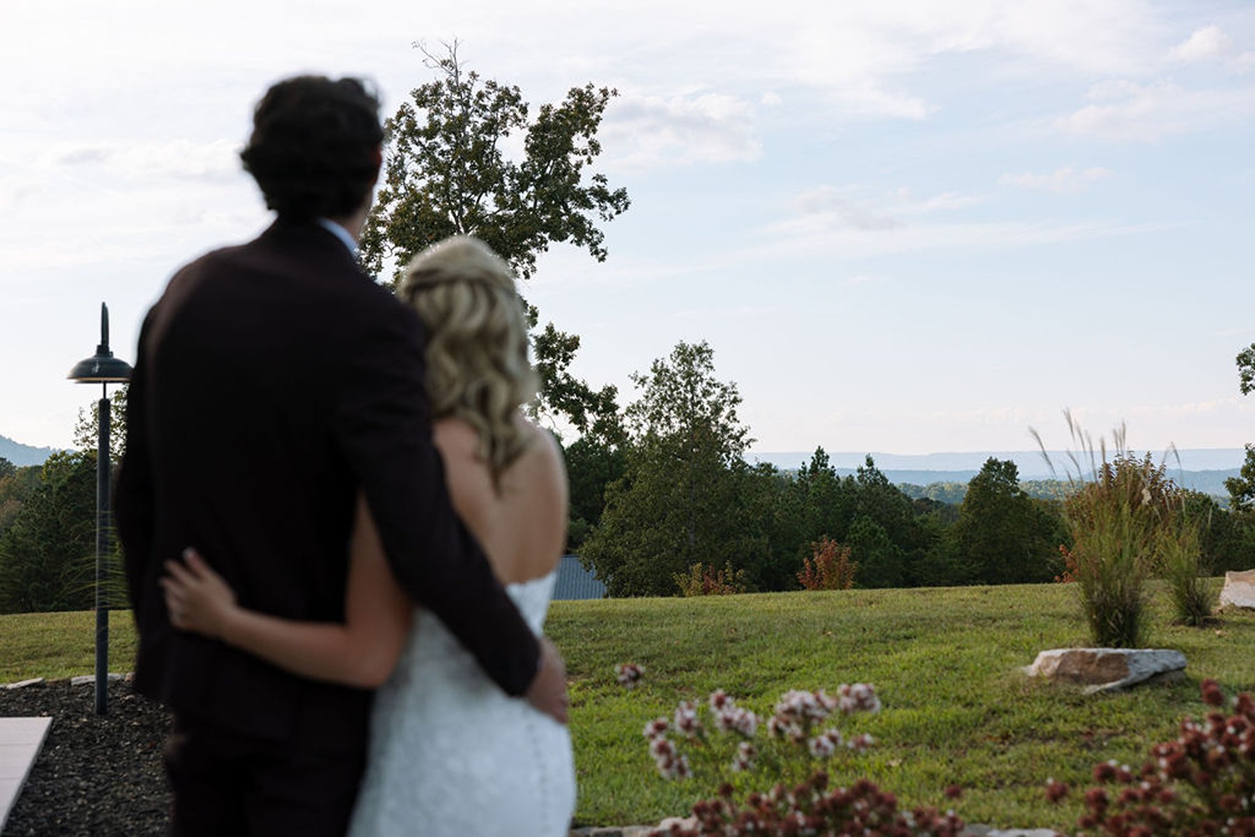 Couple embracing from behind while overlooking quiet countryside view