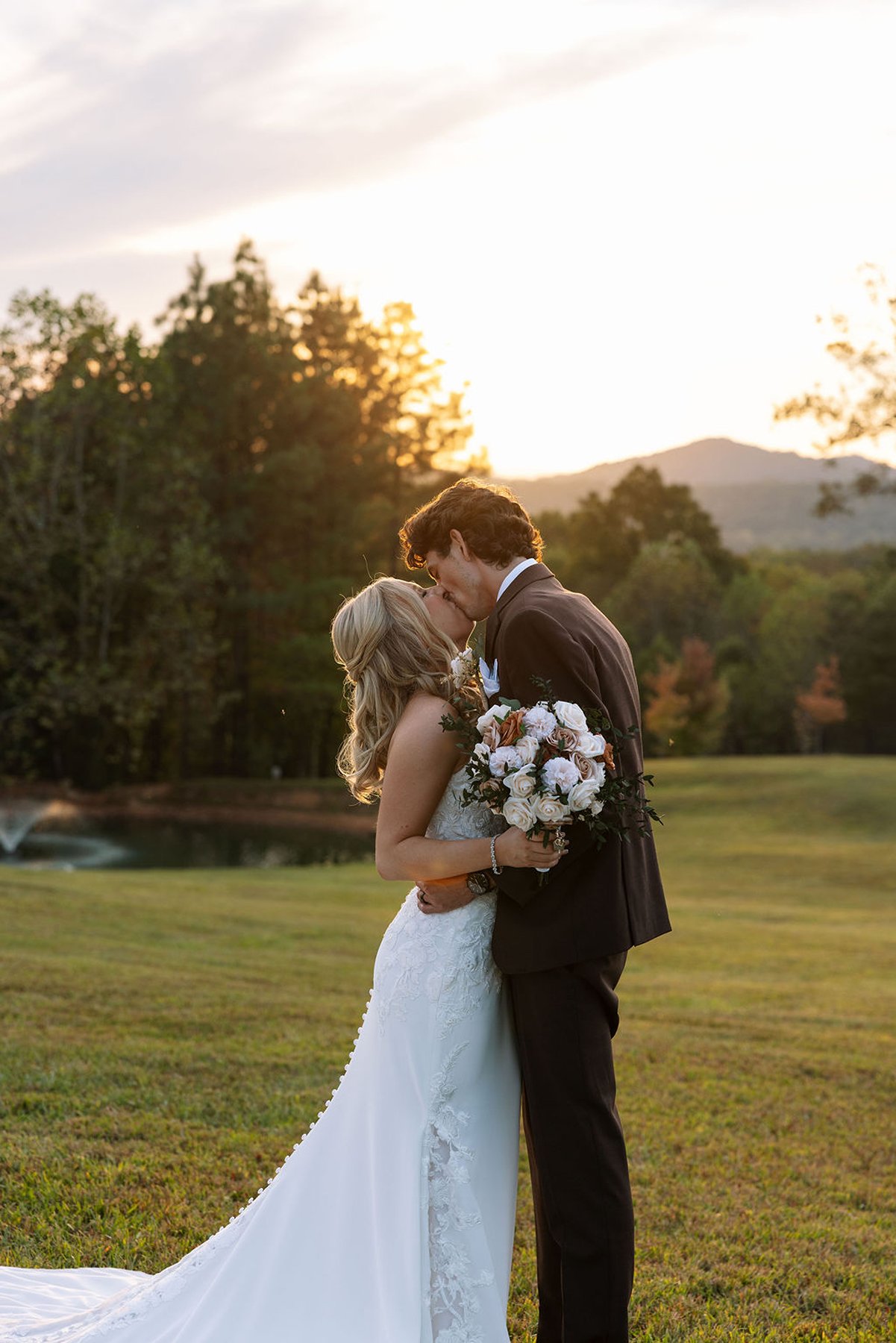 Tennessee wedding couple kissing in golden light with bouquet and soft landscape
